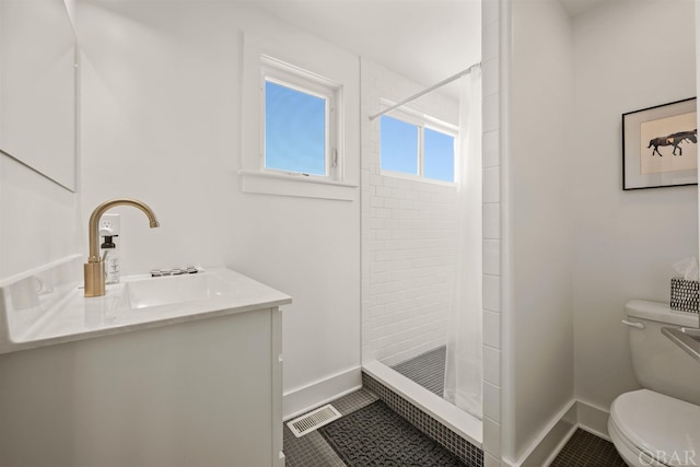 bathroom with toilet, a stall shower, vanity, tile patterned flooring, and baseboards