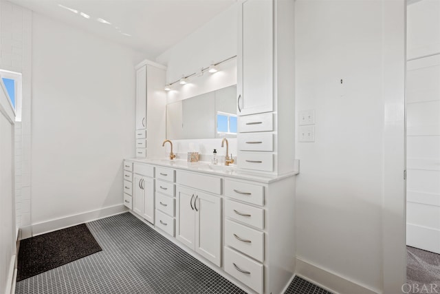 full bathroom featuring a sink, baseboards, and double vanity