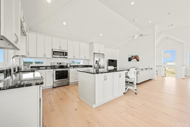 kitchen featuring light wood-style flooring, a kitchen island, stainless steel appliances, white cabinetry, and a sink