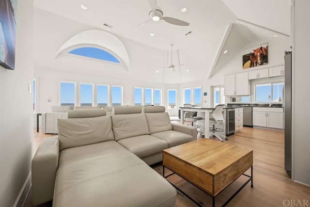 living room featuring beverage cooler, visible vents, light wood-style flooring, and a ceiling fan