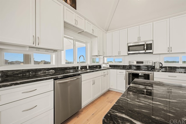 kitchen with a sink, appliances with stainless steel finishes, white cabinets, and dark stone countertops