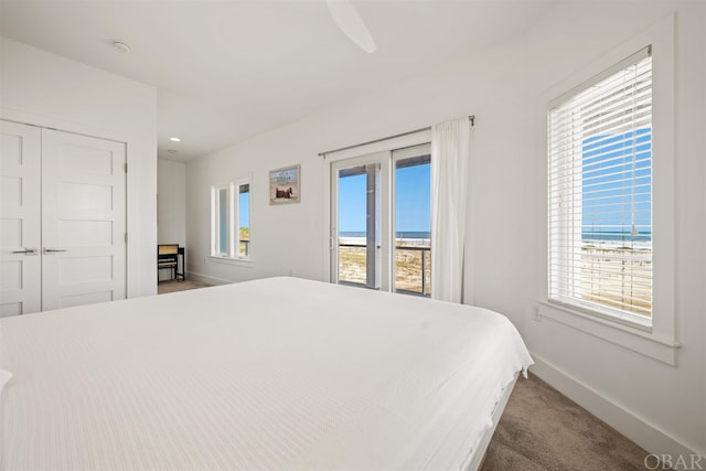 bedroom with carpet, a closet, a water view, access to outside, and baseboards