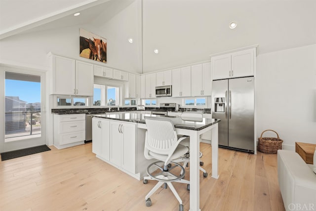 kitchen featuring a breakfast bar area, light wood-style flooring, white cabinets, appliances with stainless steel finishes, and a center island