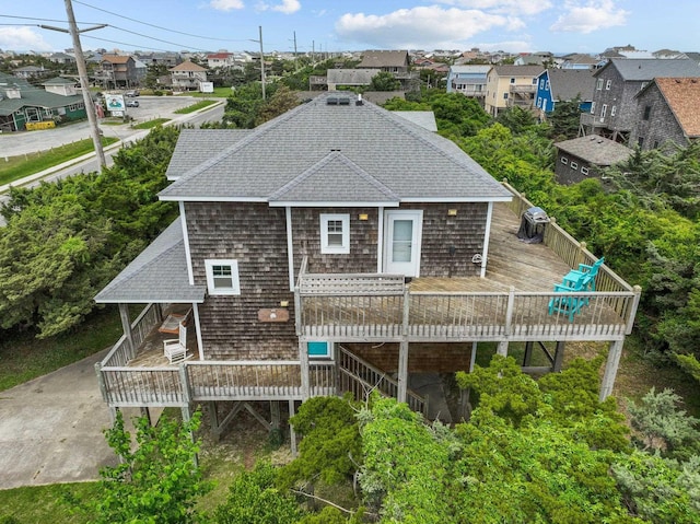 back of property featuring a shingled roof, a wooden deck, and a residential view