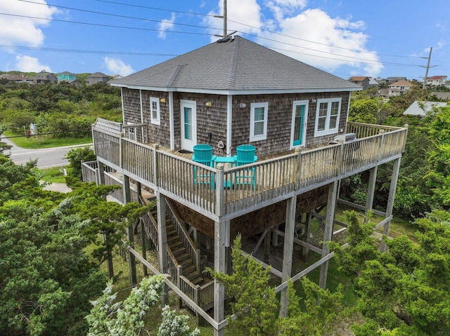 back of house featuring roof with shingles, a deck, and stairway