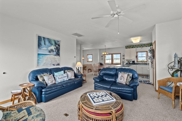 living area with visible vents, ceiling fan, and light carpet