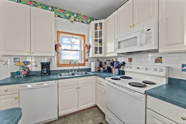 kitchen featuring a sink, dark countertops, white cabinets, and white appliances