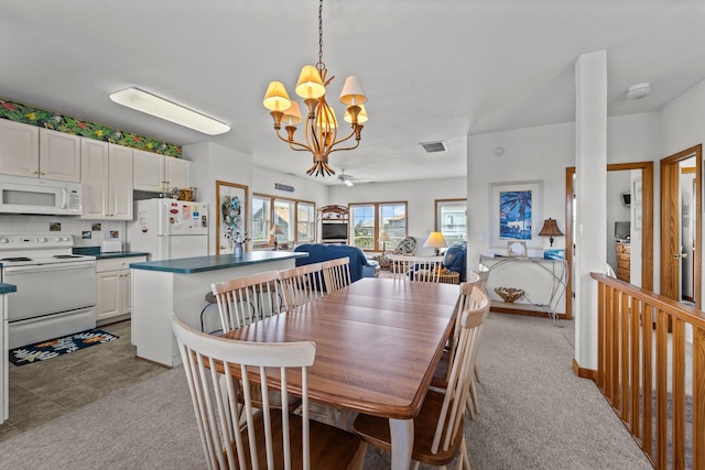 dining space with light colored carpet, a chandelier, and visible vents