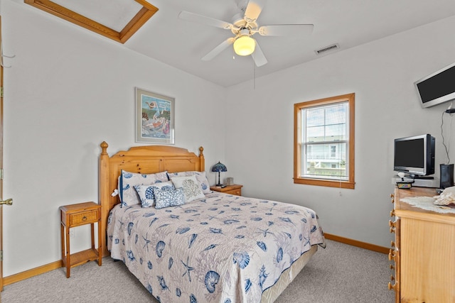 bedroom with visible vents, baseboards, attic access, light colored carpet, and a ceiling fan