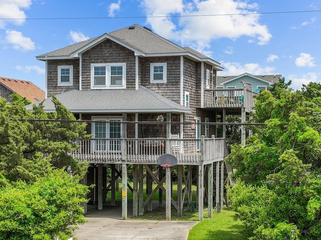 view of front facade with a deck, driveway, roof with shingles, and a carport