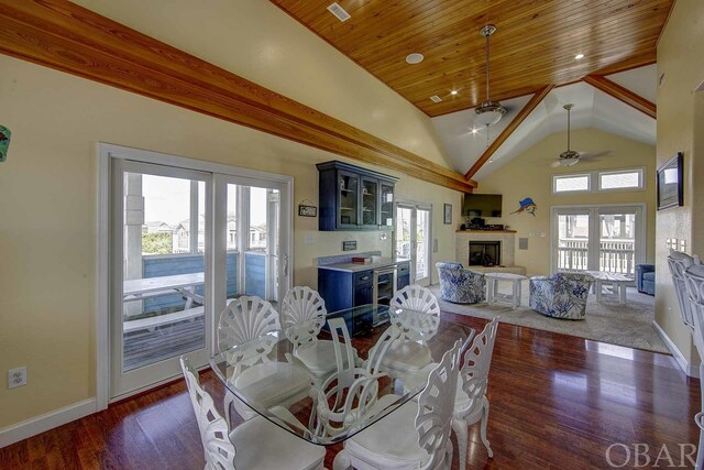 dining room featuring baseboards, dark wood finished floors, a tile fireplace, wood ceiling, and high vaulted ceiling