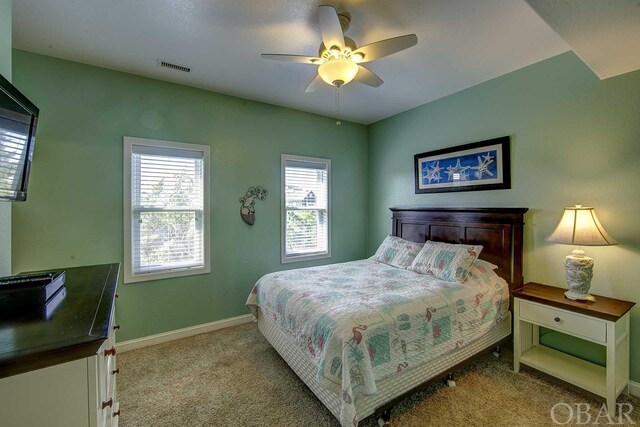 bedroom with baseboards, a ceiling fan, visible vents, and light colored carpet