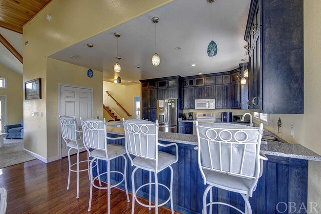 kitchen featuring white appliances, glass insert cabinets, dark brown cabinets, and a center island