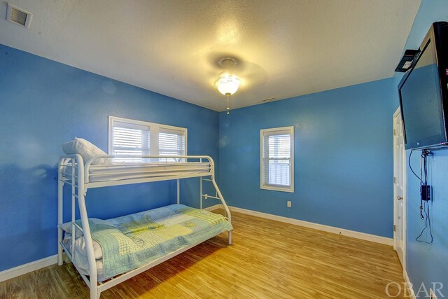 bedroom with wood finished floors, visible vents, and baseboards