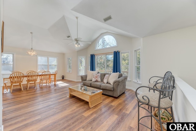 living room with a healthy amount of sunlight, light wood finished floors, visible vents, and vaulted ceiling