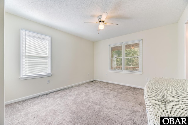 unfurnished room featuring baseboards, a textured ceiling, a ceiling fan, and carpet flooring