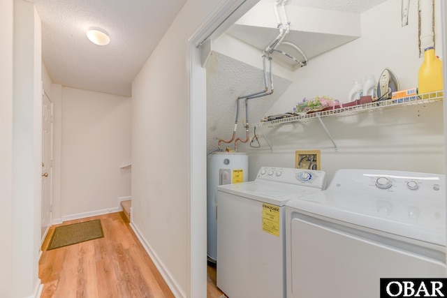 clothes washing area featuring light wood finished floors, laundry area, electric water heater, a textured ceiling, and separate washer and dryer