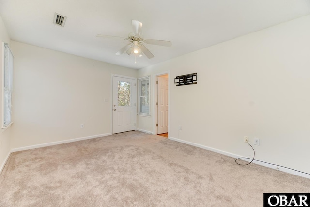 carpeted empty room featuring baseboards, visible vents, and ceiling fan