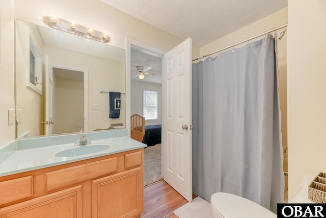 full bath with toilet, ceiling fan, wood finished floors, a textured ceiling, and vanity