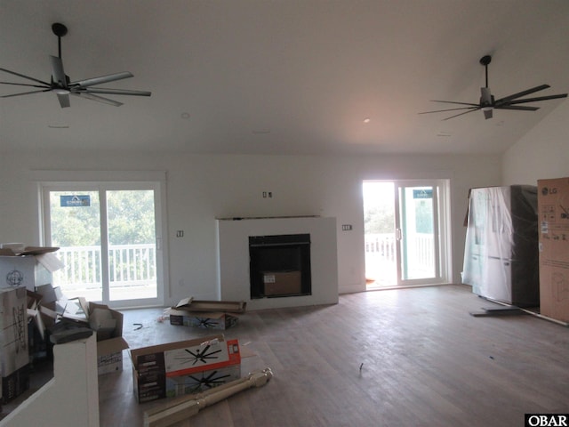 living area featuring a healthy amount of sunlight, a fireplace, a ceiling fan, and wood finished floors