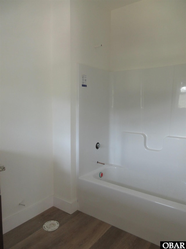 bathroom featuring shower / washtub combination, baseboards, and wood finished floors