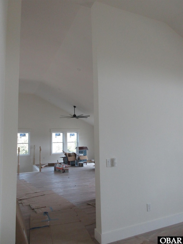 corridor with high vaulted ceiling, baseboards, and wood finished floors