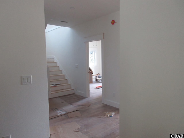 corridor with stairs, wood finished floors, and baseboards