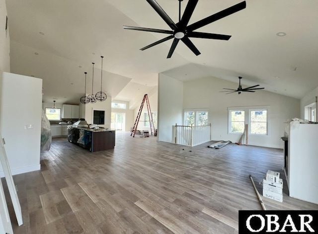 unfurnished living room with ceiling fan, wood finished floors, and high vaulted ceiling