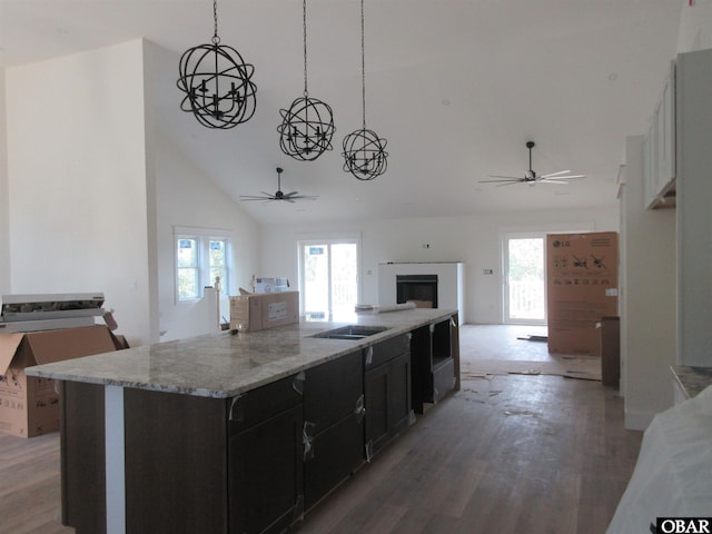 kitchen with high vaulted ceiling, dark cabinetry, open floor plan, light wood finished floors, and black electric stovetop