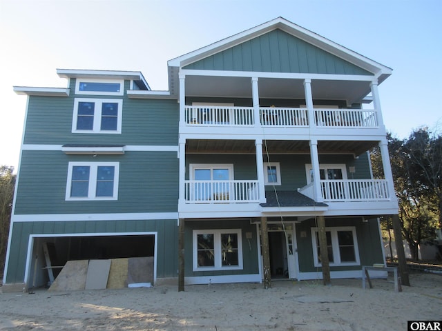 coastal inspired home with a garage, a balcony, and board and batten siding