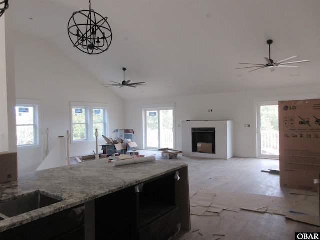 kitchen with light stone countertops, a fireplace, a wealth of natural light, and high vaulted ceiling