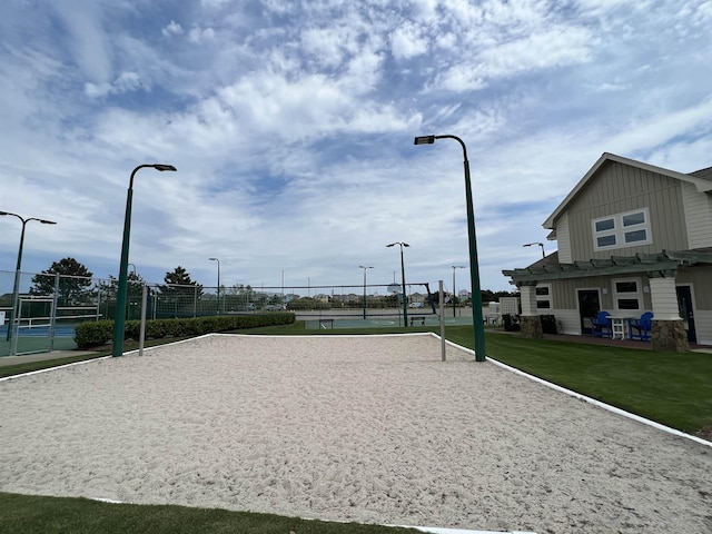 surrounding community featuring a lawn, a tennis court, volleyball court, and fence