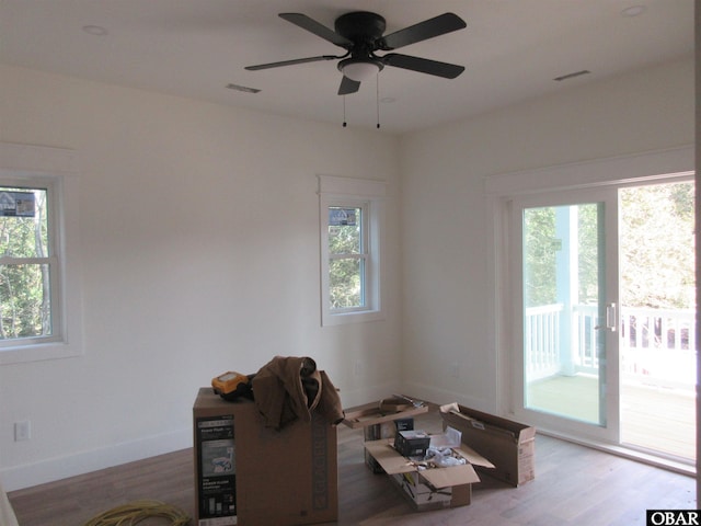 living area featuring visible vents, a ceiling fan, baseboards, and wood finished floors