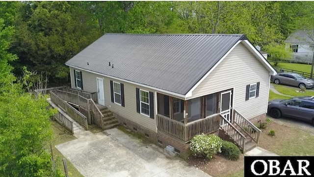 rear view of property featuring a wooded view, crawl space, stairs, and metal roof