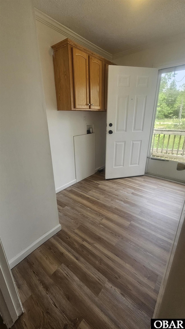 laundry room featuring dark wood-type flooring, hookup for a washing machine, cabinet space, and ornamental molding