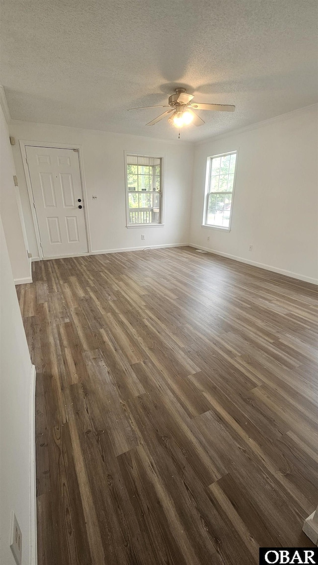 empty room featuring ceiling fan, baseboards, dark wood-style flooring, and a textured ceiling