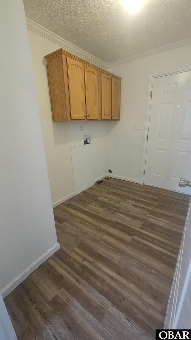 washroom with crown molding, a textured ceiling, cabinet space, dark wood finished floors, and washer hookup