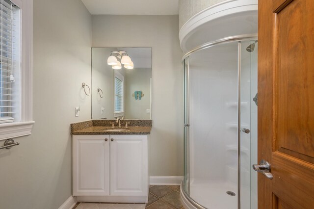 full bathroom with a stall shower, tile patterned flooring, vanity, and baseboards