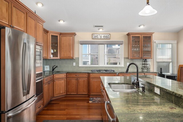 kitchen with brown cabinets, visible vents, stainless steel appliances, and a sink