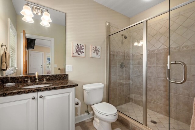 full bathroom featuring a stall shower, baseboards, vanity, and toilet