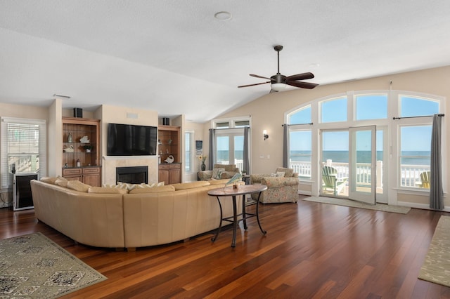 living room featuring dark wood-style floors, plenty of natural light, vaulted ceiling, and a fireplace