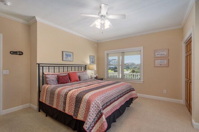 carpeted bedroom with crown molding, baseboards, and ceiling fan