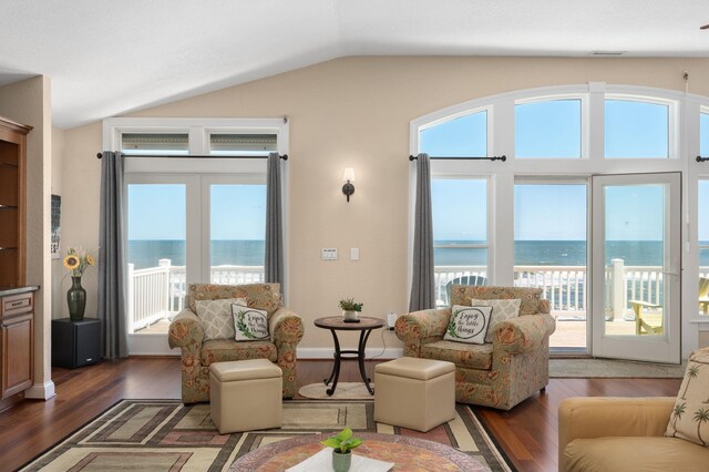 living room featuring a water view, a wealth of natural light, vaulted ceiling, and wood finished floors