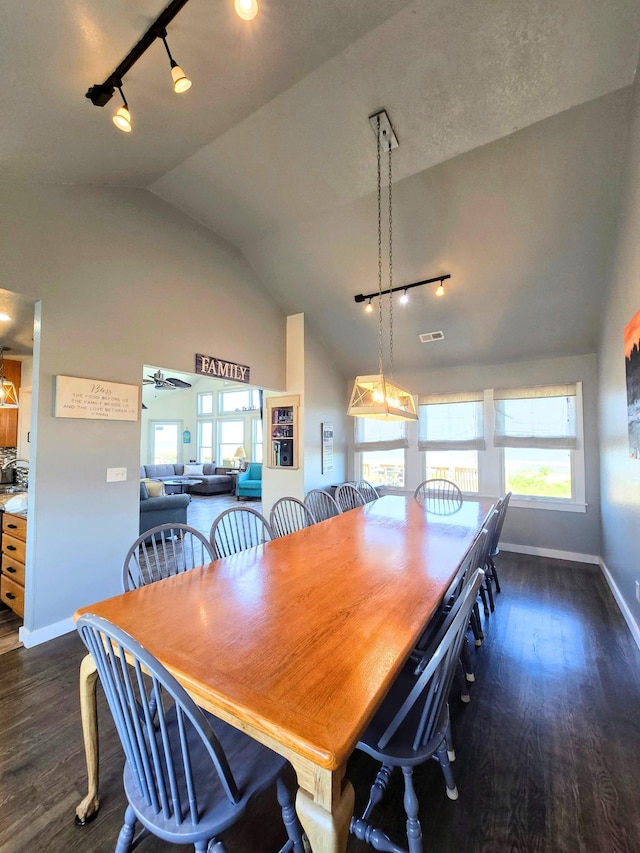 dining space featuring high vaulted ceiling, rail lighting, baseboards, and dark wood-type flooring