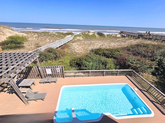 view of pool featuring a fenced in pool, a view of the beach, and a deck with water view