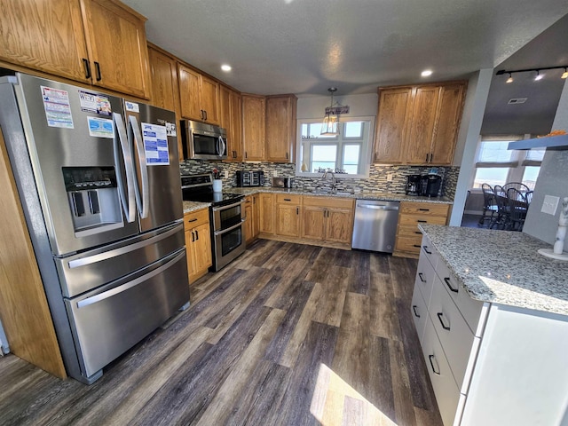 kitchen with decorative backsplash, light stone counters, dark wood-style flooring, stainless steel appliances, and white cabinetry