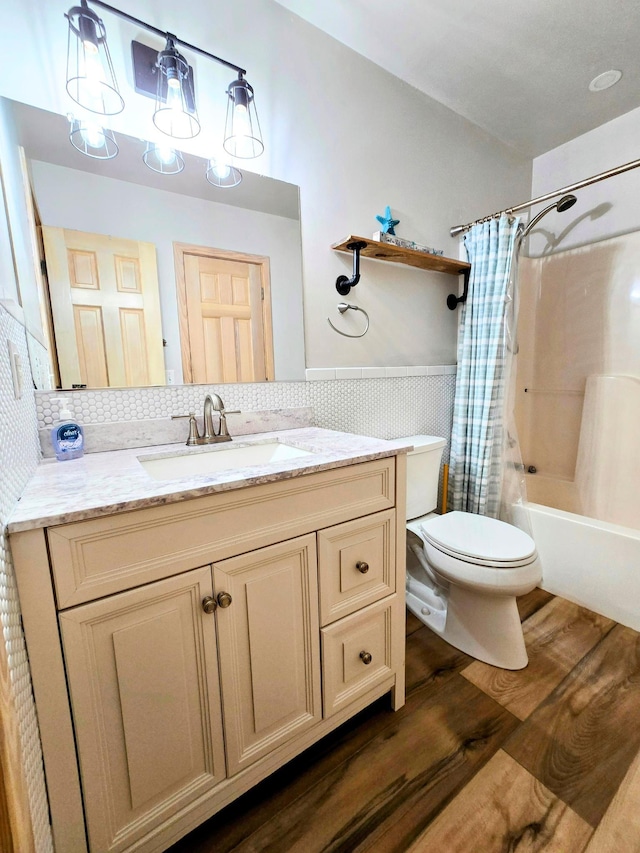 full bath featuring toilet, a wainscoted wall, vanity, tile walls, and shower / bath combo