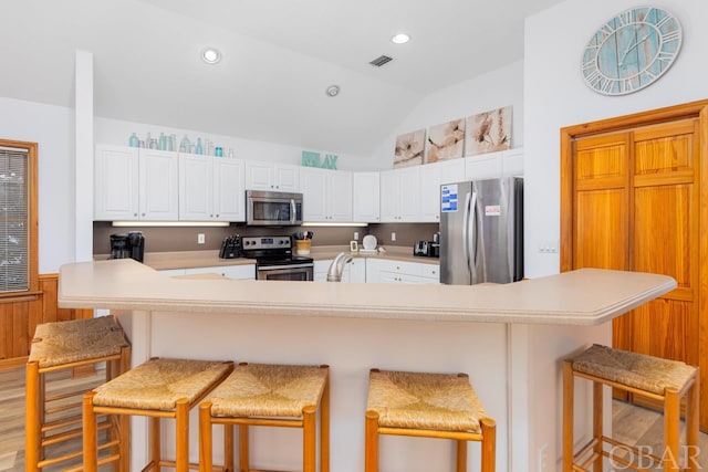 kitchen with stainless steel appliances, light countertops, a breakfast bar area, and white cabinetry