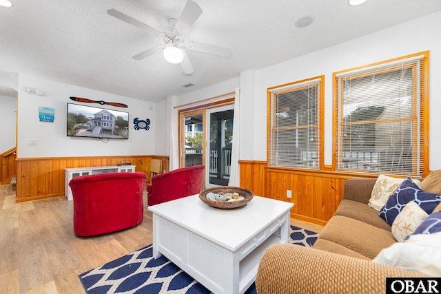 living area featuring light wood-style floors, wainscoting, wood walls, and a textured ceiling