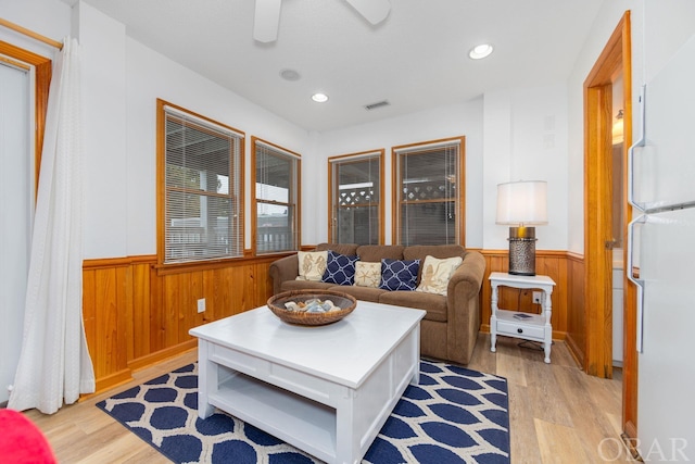 living area featuring a wainscoted wall, visible vents, and wooden walls